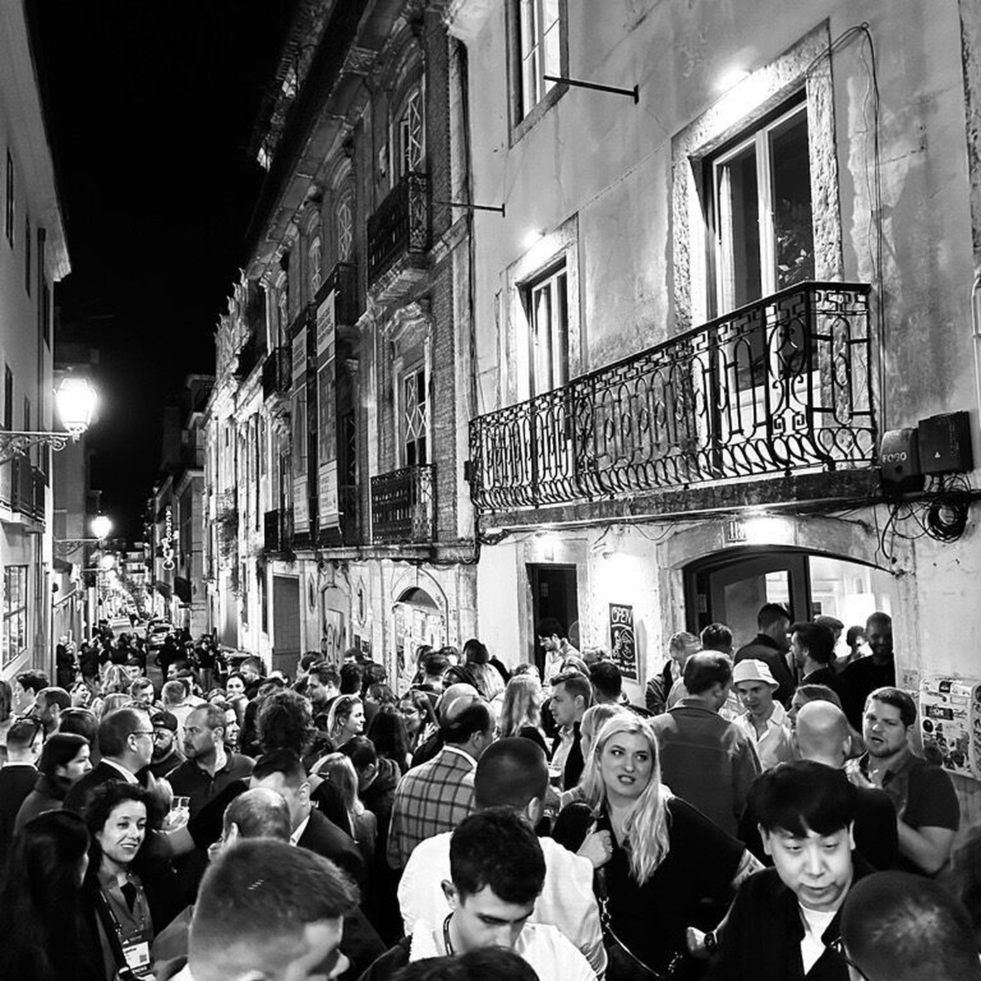 A crowd filling a narrow street outside a late-night venue